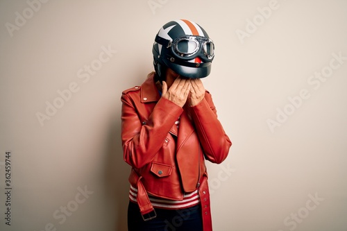 Middle age motorcyclist woman wearing motorcycle helmet and jacket over white background with sad expression covering face with hands while crying. Depression concept. © Krakenimages.com