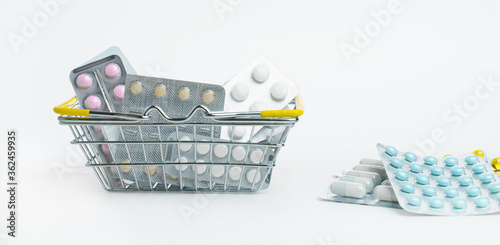 Various Pills in blisters are in a small shopping basket on a white background. Sale of drugs in stores and pharmacies. Health and medicine.
