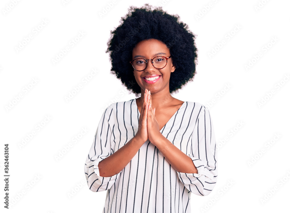 Young african american woman wearing casual clothes and glasses praying with hands together asking for forgiveness smiling confident. Young african american woman wearing casual clothes and glasses praying with hands together asking for forgiveness smiling confident.
