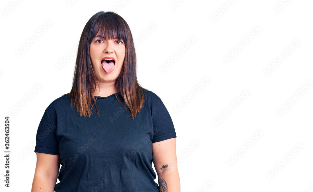 Fototapeta premium Young plus size woman wearing casual clothes sticking tongue out happy with funny expression. emotion concept.