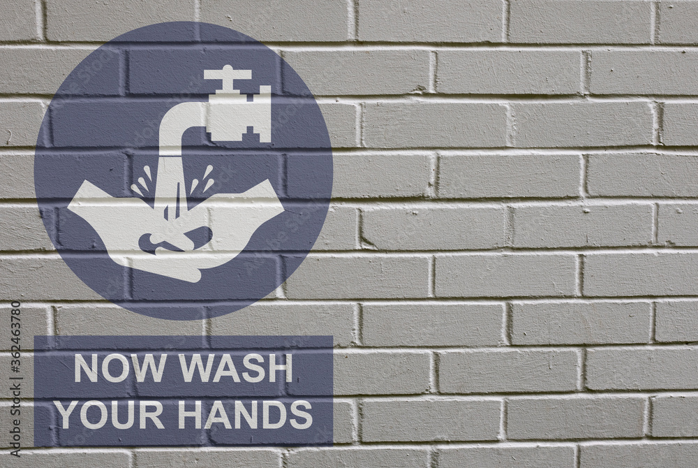 Obraz premium White decayed faded brick wall background with now wash your hands message sign to stop the spread of the worldwide pandemic