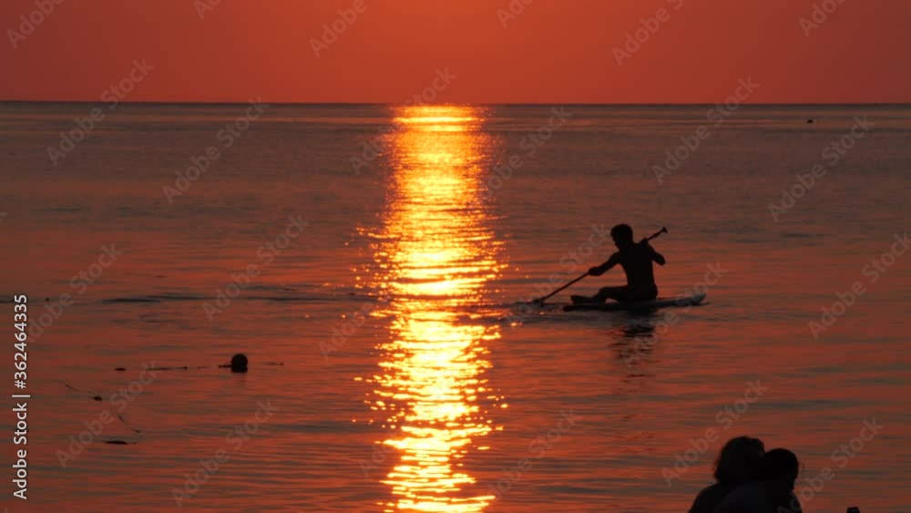 Training with board and paddle during sunset with golden reflection on the ocean. Training with board and paddle during sunset with golden reflection on the ocean.