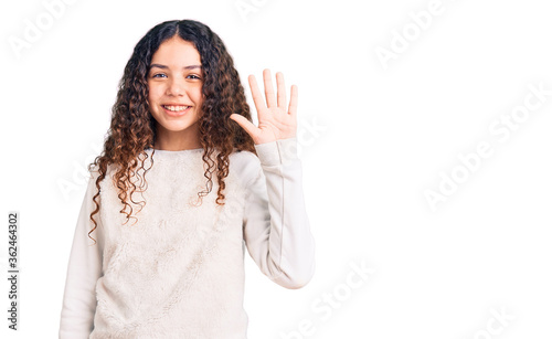 Beautiful kid girl with curly hair wearing casual clothes showing and pointing up with fingers number five while smiling confident and happy.