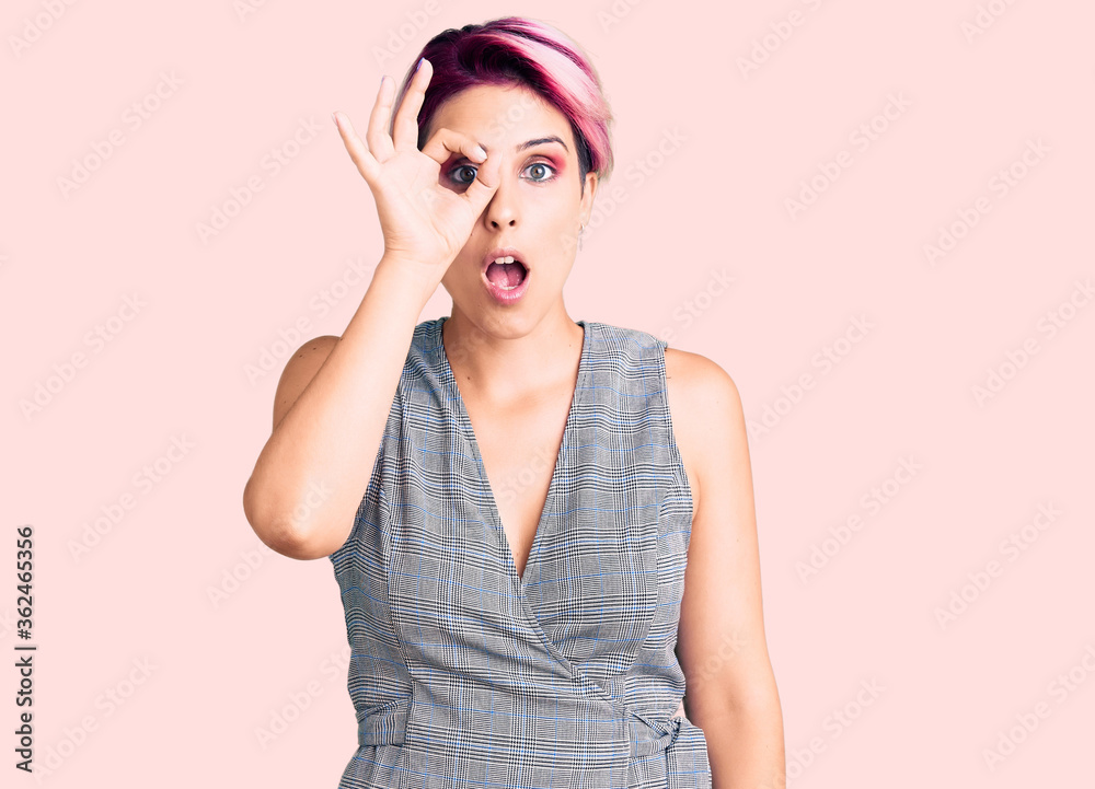 Young beautiful woman with pink hair wearing casual clothes doing ok gesture shocked with surprised face, eye looking through fingers. unbelieving expression. Young beautiful woman with pink hair wearing casual clothes doing ok gesture shocked with surprised face, eye looking through fingers. unbelieving expression.