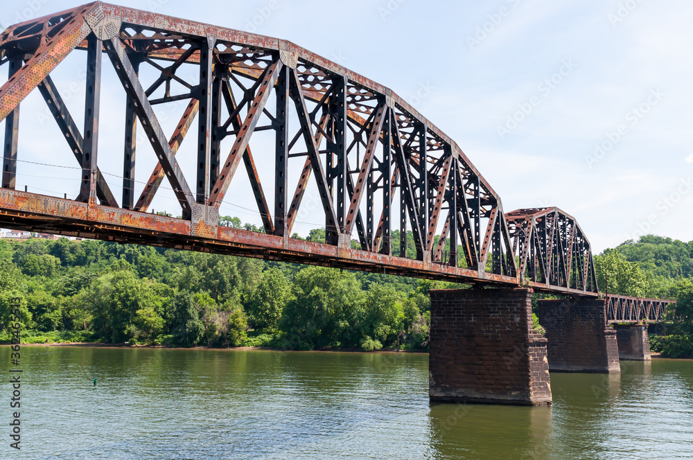 Naklejka premium An old steel railroad trestle bridge over the Monongahela River in Homestead, Pennsylvania, USA on a sunny summer day