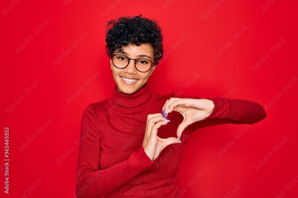 Young beautiful african american afro woman wearing turtleneck sweater and glasses smiling in love doing heart symbol shape with hands. Romantic concept. Young beautiful african american afro woman wearing turtleneck sweater and glasses smiling in love doing heart symbol shape with hands. Romantic concept.