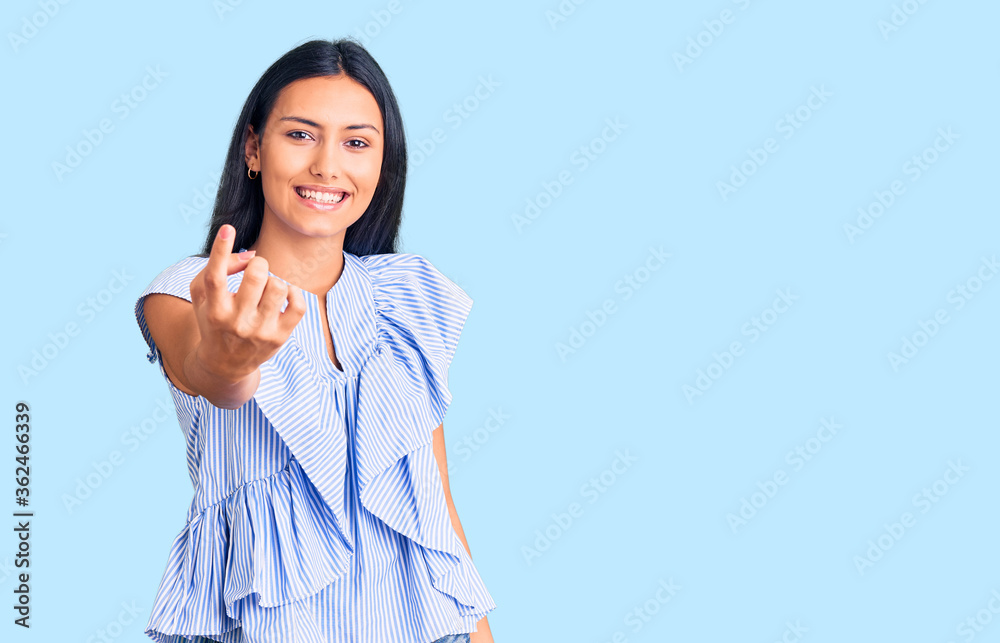 Young beautiful latin girl wearing casual clothes beckoning come here gesture with hand inviting welcoming happy and smiling Young beautiful latin girl wearing casual clothes beckoning come here gesture with hand inviting welcoming happy and smiling