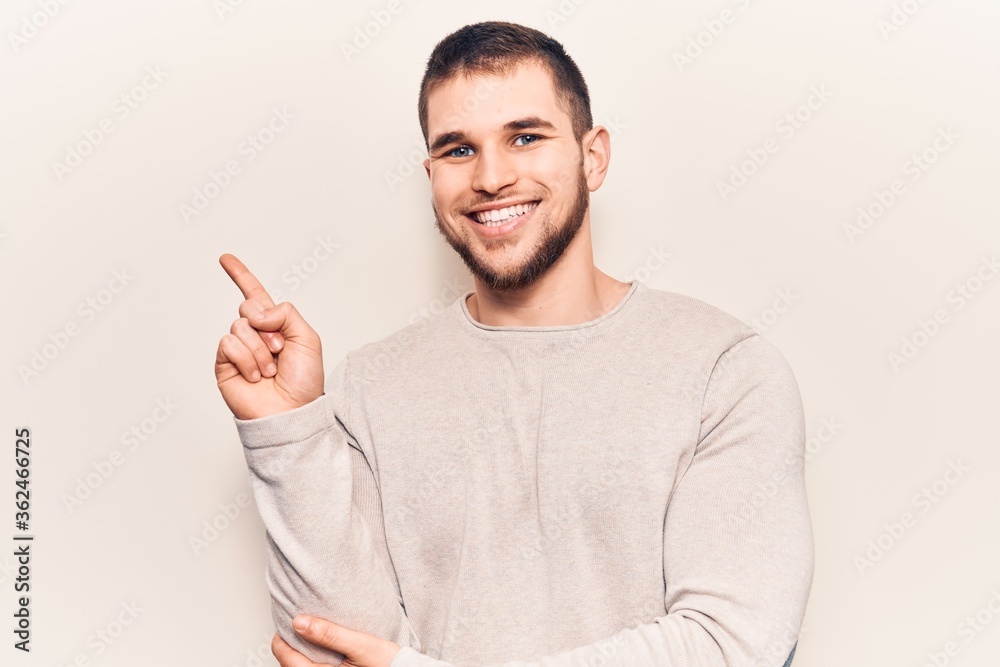 Young handsome man wearing casual sweater smiling happy pointing with hand and finger to the side Young handsome man wearing casual sweater smiling happy pointing with hand and finger to the side