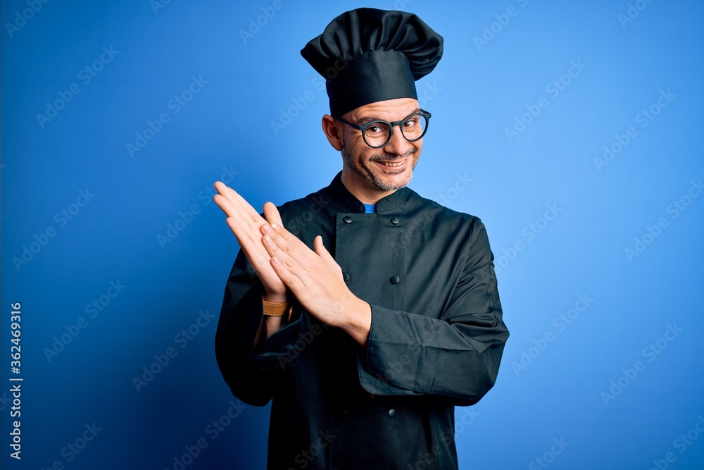 Young handsome chef man wearing cooker uniform and hat over isolated blue background clapping and applauding happy and joyful, smiling proud hands together Young handsome chef man wearing cooker uniform and hat over isolated blue background clapping and applauding happy and joyful, smiling proud hands together