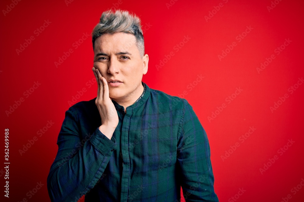 Young handsome modern man wearing elegant green shirt over red isolated background touching mouth with hand with painful expression because of toothache or dental illness on teeth. Dentist