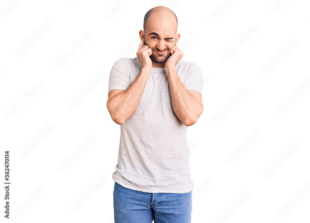 Young handsome man wearing casual t shirt covering ears with fingers with annoyed expression for the noise of loud music. deaf concept. Young handsome man wearing casual t shirt covering ears with fingers with annoyed expression for the noise of loud music. deaf concept.