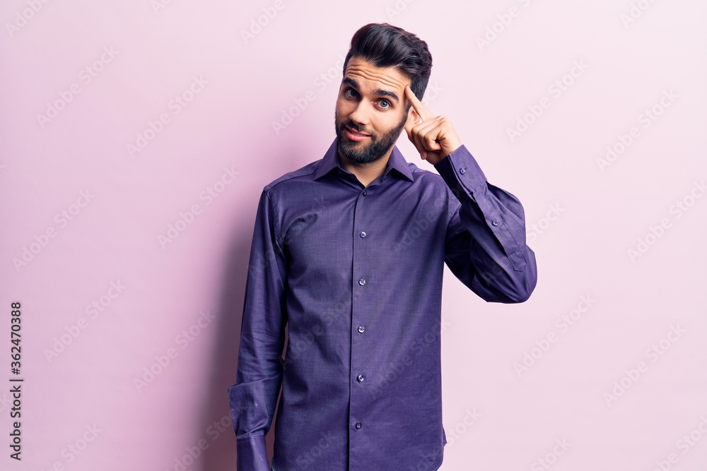 Young handsome man with beard wearing casual shirt smiling pointing to head with one finger, great idea or thought, good memory Young handsome man with beard wearing casual shirt smiling pointing to head with one finger, great idea or thought, good memory