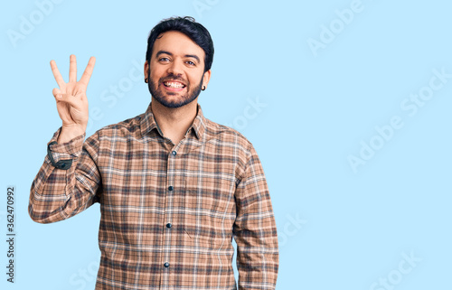 Young hispanic man wearing casual clothes showing and pointing up with fingers number three while smiling confident and happy.