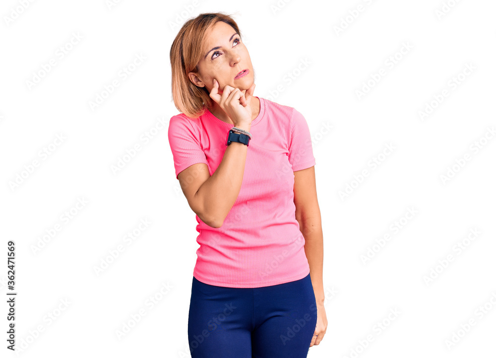 Young blonde woman wearing sportswear thinking worried about a question, concerned and nervous with hand on chin Young blonde woman wearing sportswear thinking worried about a question, concerned and nervous with hand on chin