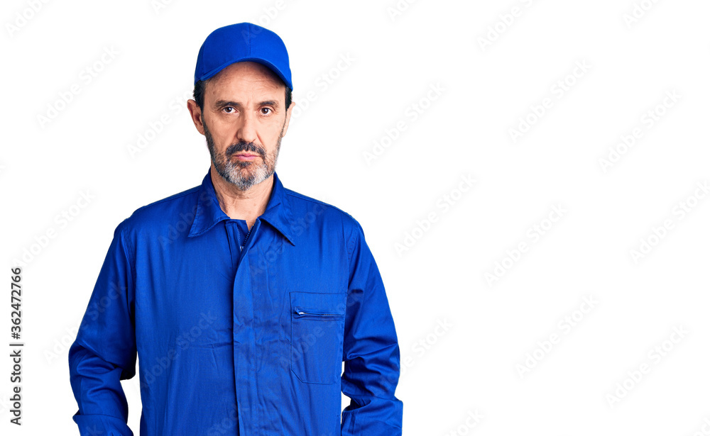 Middle age handsome man wearing mechanic uniform relaxed with serious expression on face. simple and natural looking at the camera.