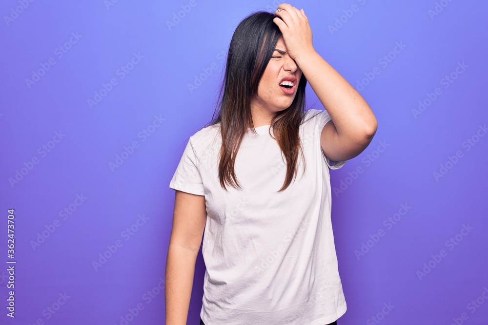 Young beautiful brunette woman wearing casual t-shirt standing over purple background surprised with hand on head for mistake, remember error. Forgot, bad memory concept. Young beautiful brunette woman wearing casual t-shirt standing over purple background surprised with hand on head for mistake, remember error. Forgot, bad memory concept.