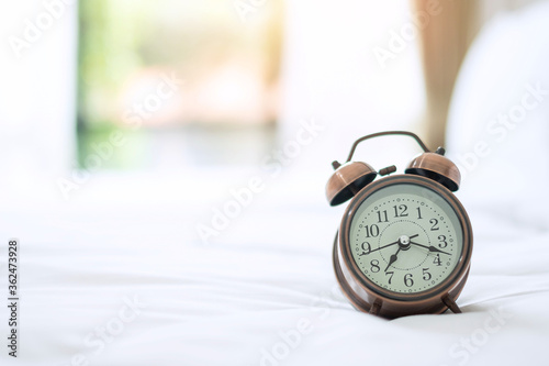 Retro alam clock on bed in the morning sunlight, wake up, fresh relax, have a nice day and daily routine concept