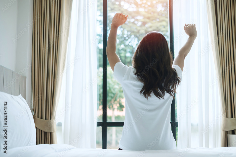 happy woman stretching in bed after waking up, young adult female rising arms and looking to window in the morning. fresh relax and have a nice day concepts happy woman stretching in bed after waking up, young adult female rising arms and looking to window in the morning. fresh relax and have a nice day concepts
