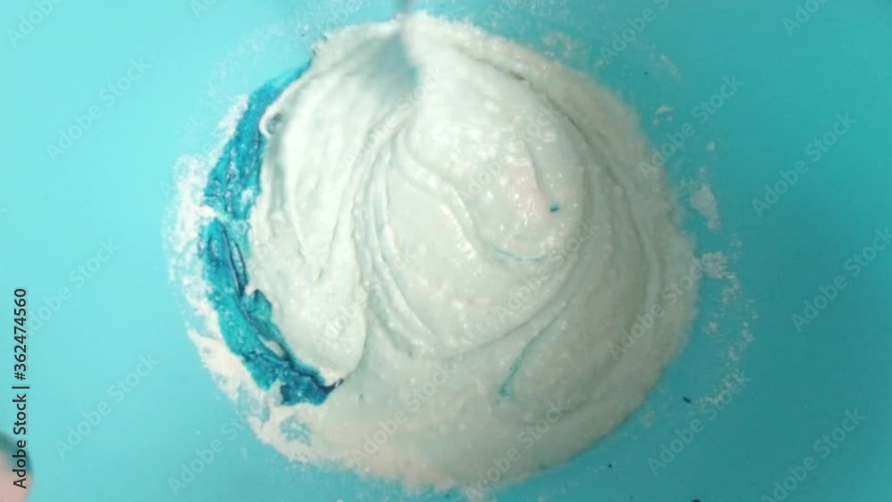 Mixing blue food colouring to sponge cake batter mixture top down view Mixing blue food colouring to sponge cake batter mixture top down view
