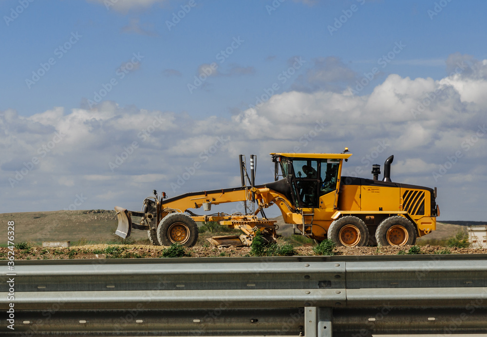 Obraz premium Grader yellow. Grader road construction, industrial machine for the construction of new roads.