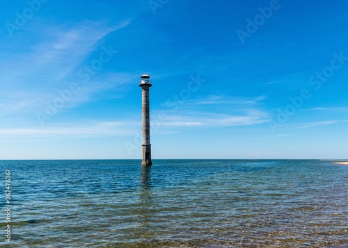 landscape with an abandoned sloping lighthouse "Kiipsaare lighthouse" on the Baltic Sea. Clear water and blue sky with white clouds. Harilaid Nature Reserve, Estonia, Baltic Sea
