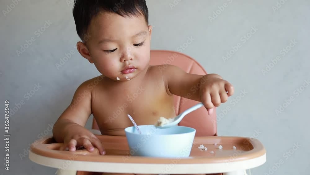 Asian baby boy eating food by himself