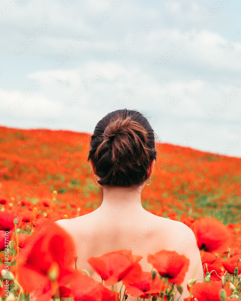 Naklejka premium young pretty woman enjoying life. standing in the middle of the filed with poppy flowers
