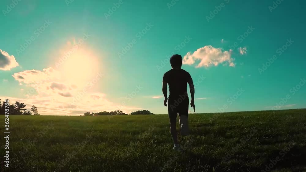 man running up a grassy hill on bright sunny day man running up a grassy hill on bright sunny day