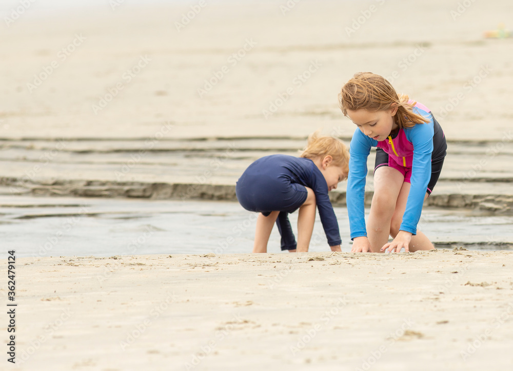 Two young children playing in the sand and water at a beach