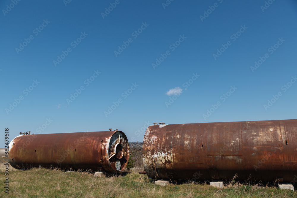 Two old abandoned rusty barrels lie in the open air on the grass Two old abandoned rusty barrels lie in the open air on the grass
