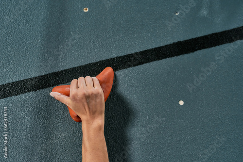 Close up of a hand of woman climbing up on rock wall in gym. Bouldering training concept photo
