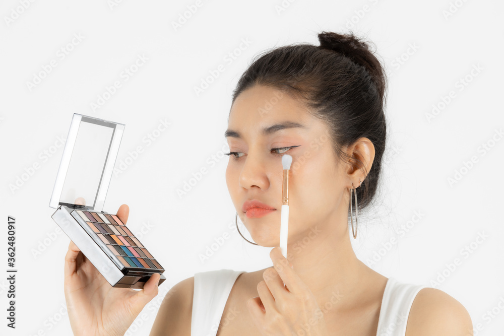 Healthy and cosmetics concept. Beauty face of young Asian woman applying make up with brush over white isolated background. Healthy and cosmetics concept. Beauty face of young Asian woman applying make up with brush over white isolated background.