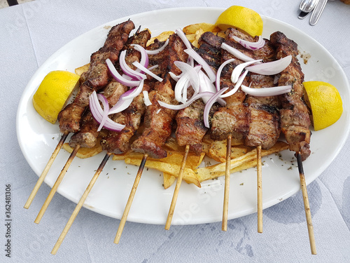 souvlakia greek tranditional food of meat onion lemon and potatoes in a plate photo