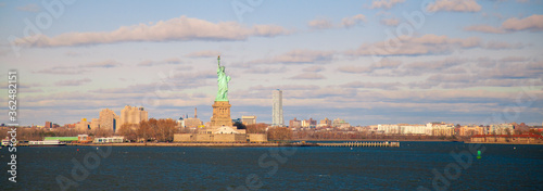 An autumn panorama captured from staten island ferry as it crosses the upper bay towards manhattan. Image features the iconic Statue of Liberty as well as the cityscape of Jersey city, New Jersey