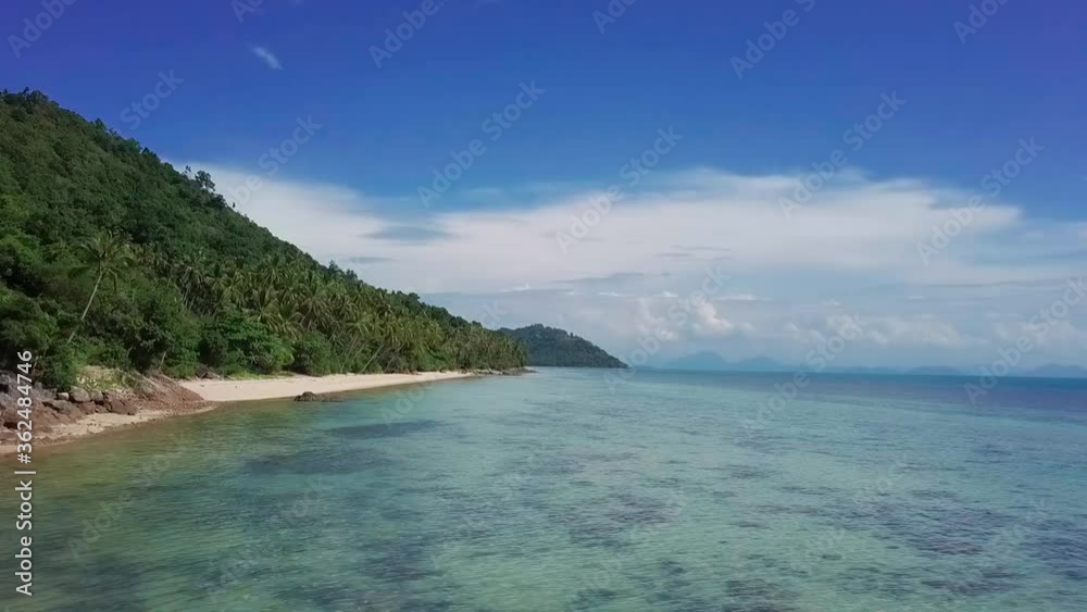 Aerial drone fly along exotic tropical beach shallow blue water and coconut palm trees in Thailand Aerial drone fly along exotic tropical beach shallow blue water and coconut palm trees in Thailand
