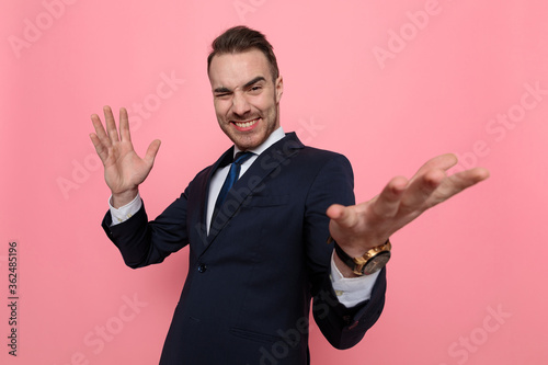 Foto enthusiastic young guy in suit holding hands in the air