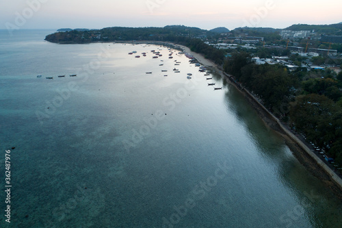 Aerial view drone shot of long tail boats at rawai beach in phuket Thailand sunset evening time.