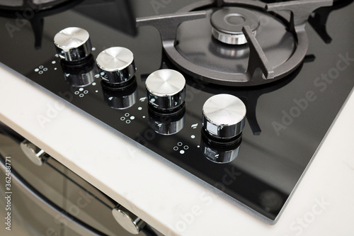 Hob cooker oven made of glass grill stainless steel control knobs selective focus over out of focus oven with burner on countertop made of ceramic stoneware background.