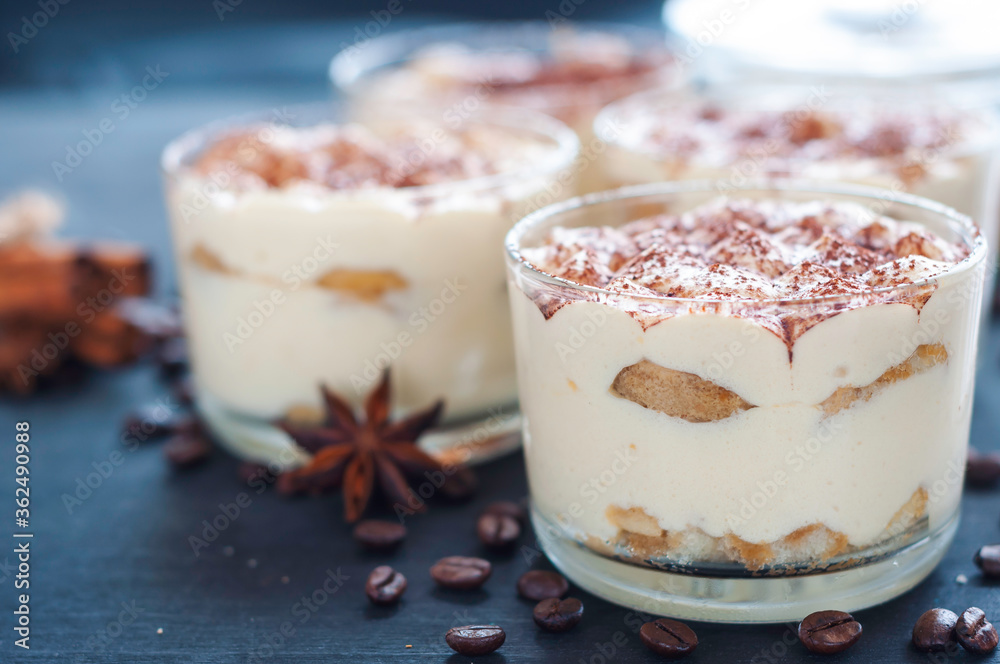 exquisite tiramisu in glasses decorated with cocoa powder on a dark background exquisite tiramisu in glasses decorated with cocoa powder on a dark background