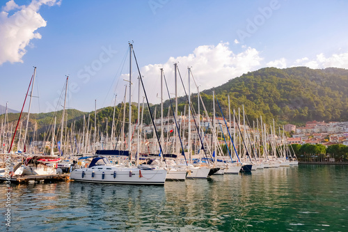 Luxury yachts docked in sea port at sunset. A stunning view of mega yachts in the port. Mountains background.