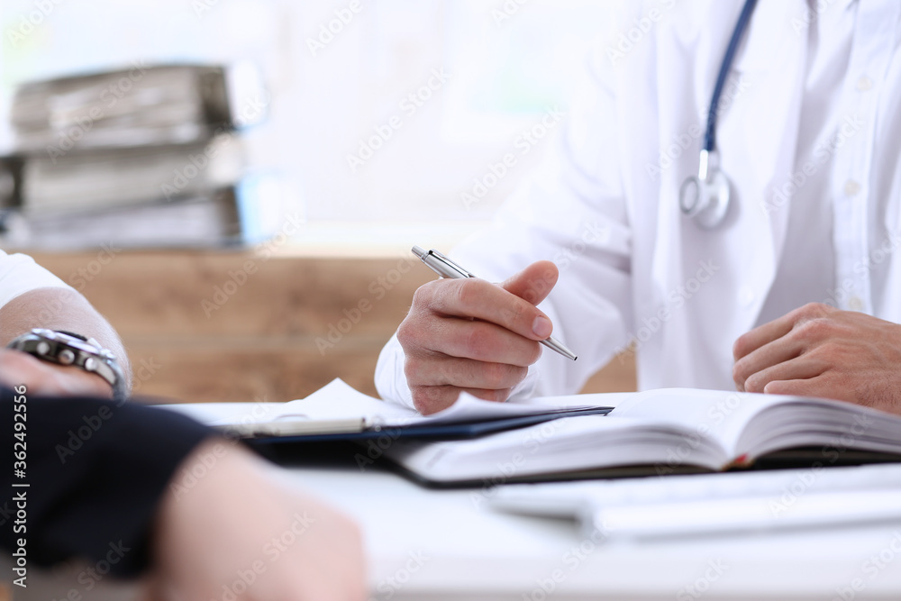 Male doctor hands hold silver pen discuss problem with family couple closeup. Motherhood, child delivery, new life or abortion, therapeutist reception service, physical, hospital and clinic concept Male doctor hands hold silver pen discuss problem with family couple closeup. Motherhood, child delivery, new life or abortion, therapeutist reception service, physical, hospital and clinic concept