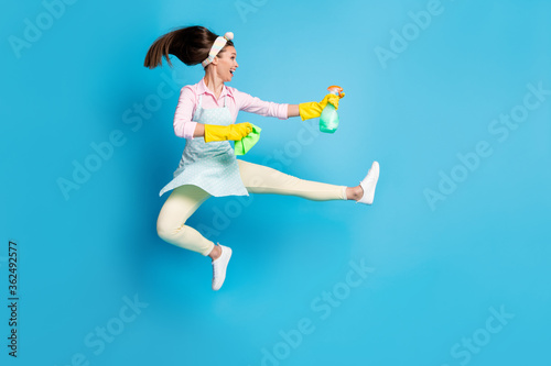 Full length body size view of her she nice attractive pretty funky funny comic childish cheerful maid jumping fighting infection dust isolated on bright vivid shine vibrant blue color background photo