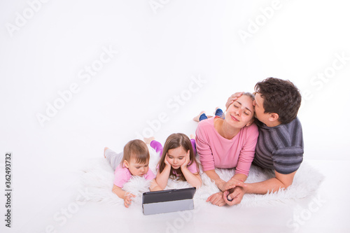 the kids are watching cartoons on the tablet. a man and a woman embrace. Family vacation, joint pastime. Parents with girls on the floor © aaalll3110
