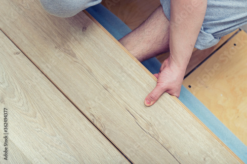 Laying laminate. Man laying laminate flooring in construction concept.