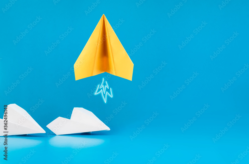 one yellow paper airplane takes off on a blue background Stock Photo