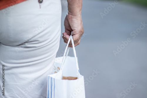 A female hand holds an eco-friendly paper bag in hand for transmission to a client. Safe contactless delivery. Secure e-commerce shopping for home parcel purchases.