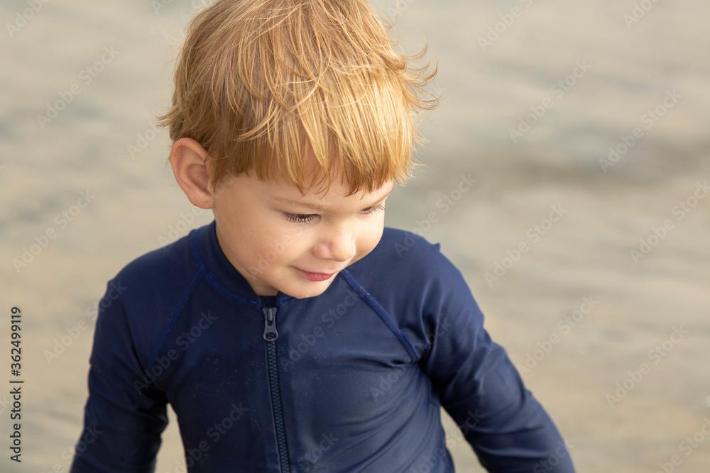 Young boy, four years old, running and playing at the beach. Blonde hair and navy swimming suit, smiling and laughing. Young boy, four years old, running and playing at the beach. Blonde hair and navy swimming suit, smiling and laughing.