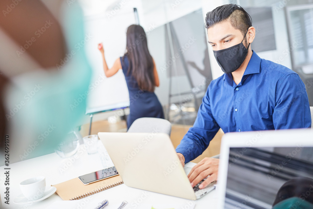 Businessman with face mask is typing on laptop