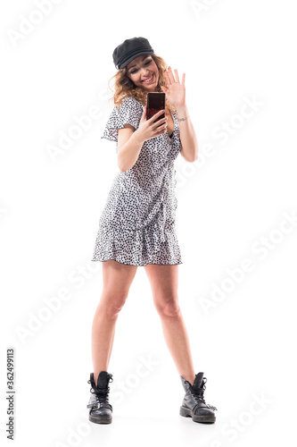 Happy young pretty woman in stylish clothes greeting doing cell phone video call. Full length isolated on white background.  © sharplaninac