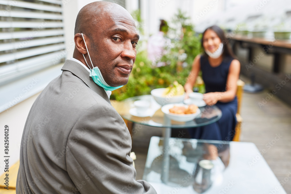 Business man with face mask on chin sitting in cafe Business man with face mask on chin sitting in cafe
